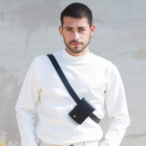 a male model wearing one of the black leather belt bags