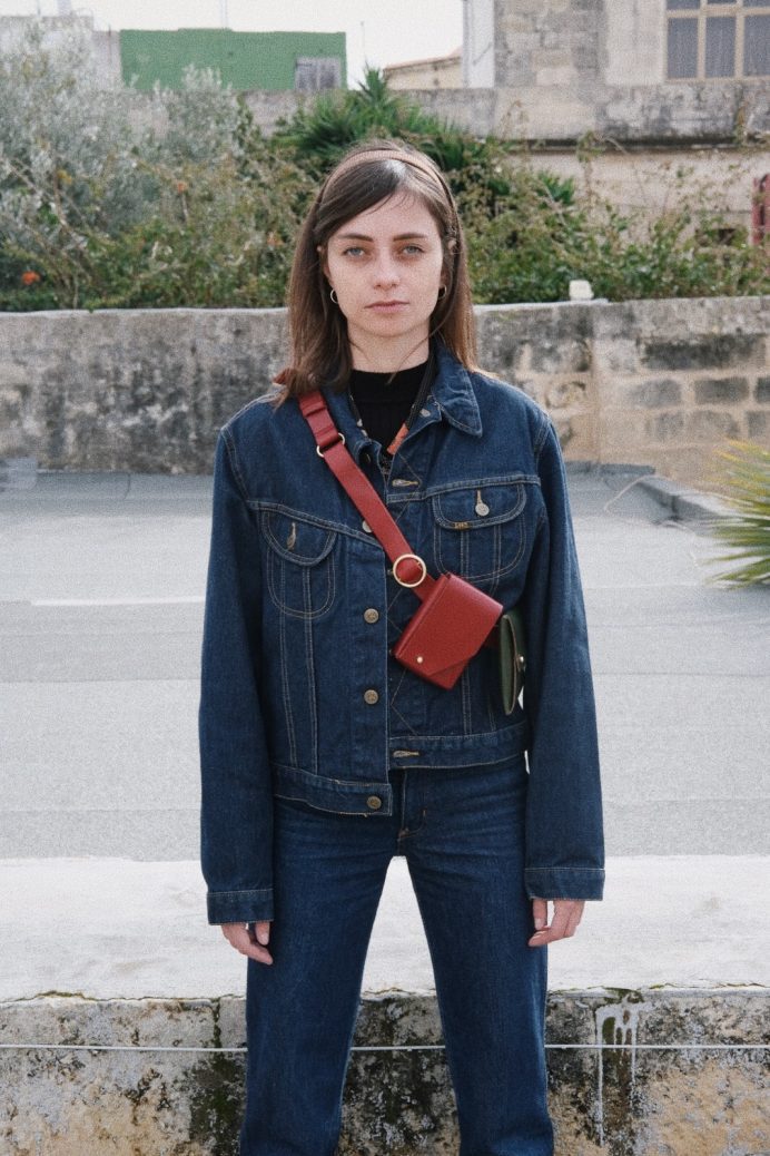 A female wearing a vintage denim outfit and a red and green fold on a red leather adjustable belt