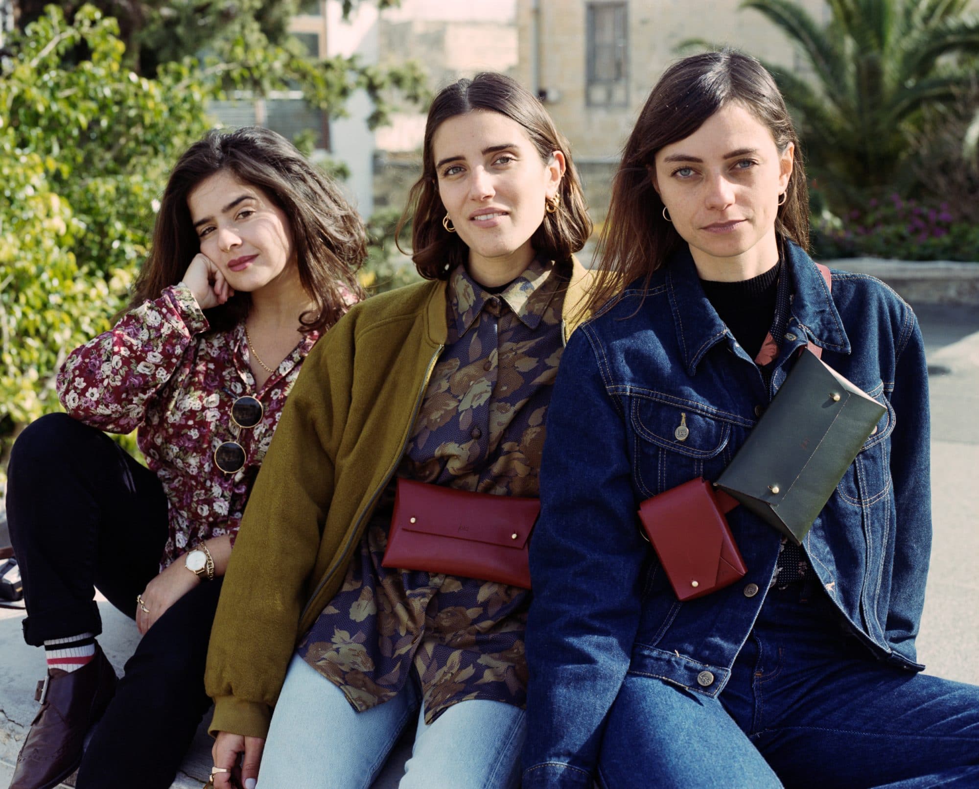 Three women wearing vintage clothes and fold leather belt bags 