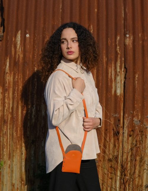 a female model wears an orange leather walking bag