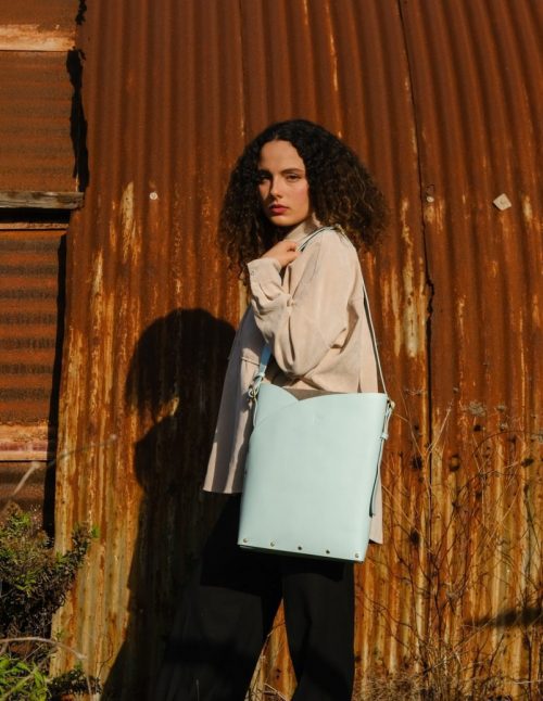 a woman wears a sky blue leather tote bag