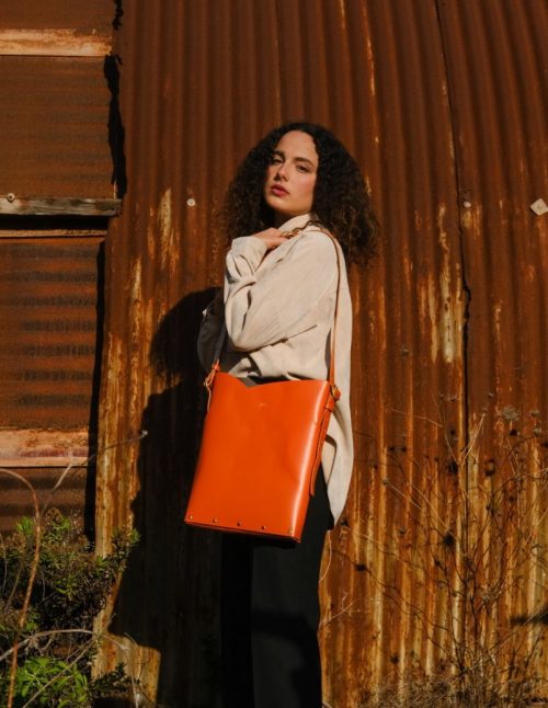 a female model wears an orange tote bag