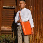 a male model wears an orange tote bag