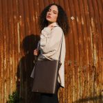 a female model wears a brown leather laptop bag