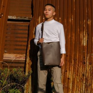 a male model wears a brown leather laptop bag